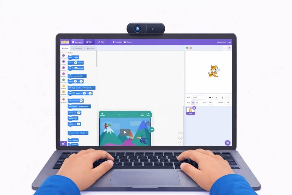 Child's hands building a project in Scratch with colorful coding blocks and the cat sprite on screen